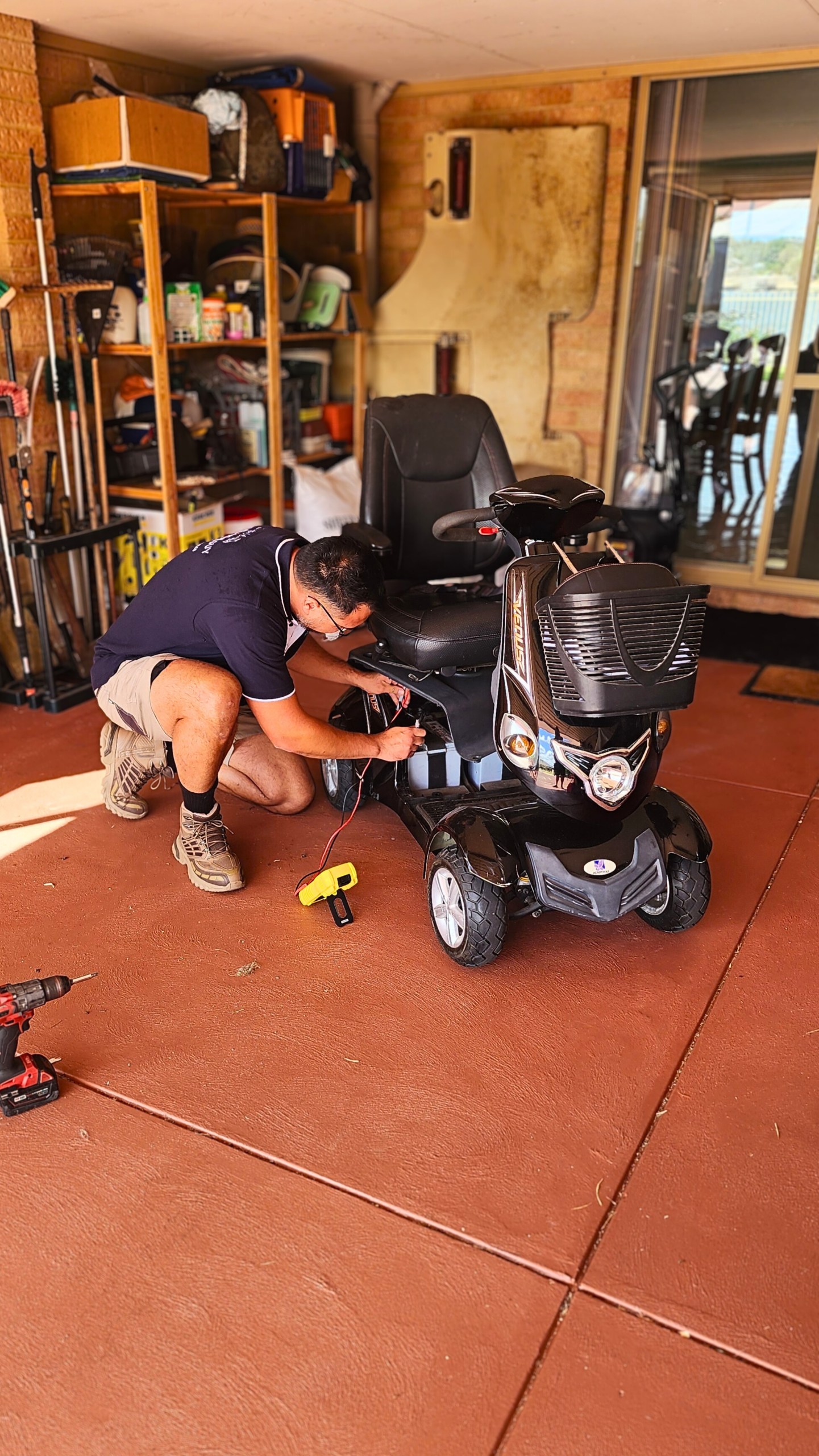 Technician performing maintenance on a mobility scooter in a garage, demonstrating repair services for My ERide Guy.