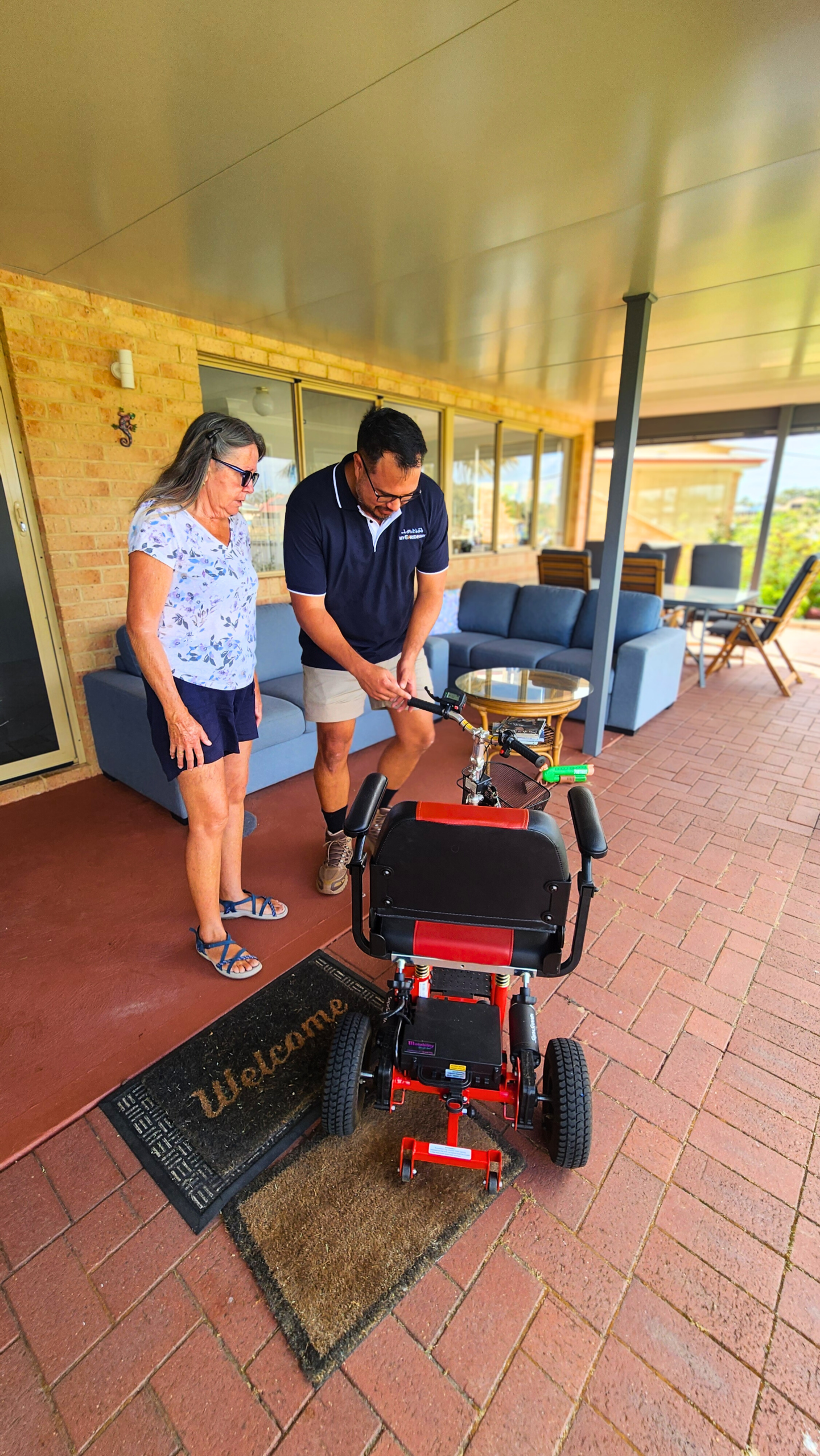 Mobile e-scooter repair service technician assisting a customer with a scooter, demonstrating hands-on support and expertise in a residential setting.